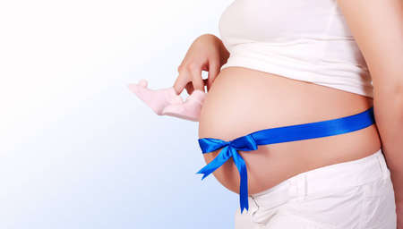 Close up image of pregnant woman tummy with blue ribbon and  babyの写真素材