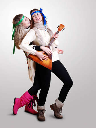 Two laughing beautiful girls dancing and plaing on balalaika  の写真素材