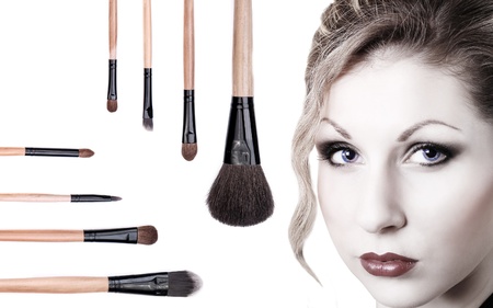 Portrait of beautiful blue-eyed girl with makeup brushesの写真素材