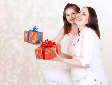 Happy smiling yong pregnant mother with little daughter and gift boxes の写真素材