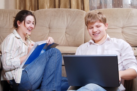 Teenage girl and boy do their homework with laptop at homeの写真素材