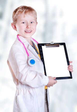 Happy smiling little boy in doctor uniform with medical toolsの写真素材