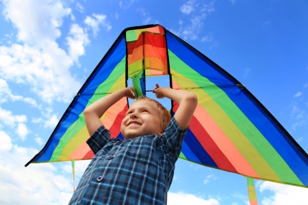 Boy with bright kite over the head on the blue sky viewの写真素材