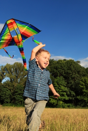 Happy little boy playing with bright kite at the outdoorの写真素材