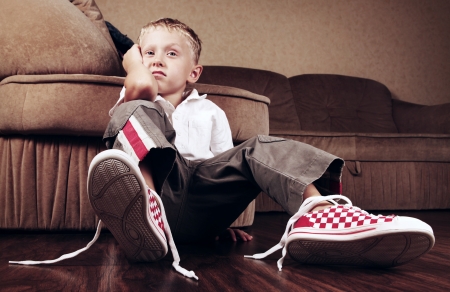 Disappointed little boy with untied laces on his bootsの写真素材