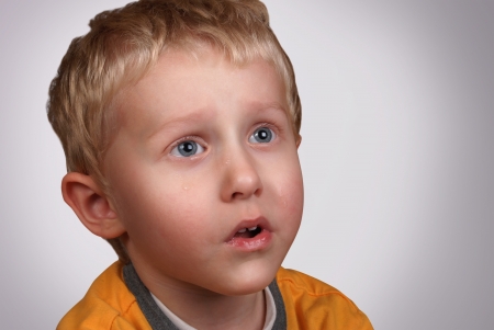 Crying boy portrait on light gray backgroundの写真素材