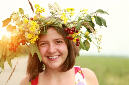 Smiling girl in wild flowers and cherry wreath の写真素材