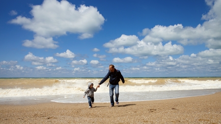 Father and son running along the sea beachの写真素材