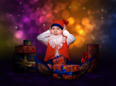Worried  little boy in gnome fancy dress with gift boxes on shining light colored backgroundの写真素材