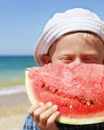 Closeup portreit boy with big watermelon piece at the seaの写真素材