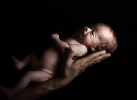 Tiny newborn baby girl on the father's hand.