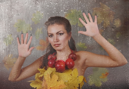 Lady Autumn looking through wet rainy windowの写真素材