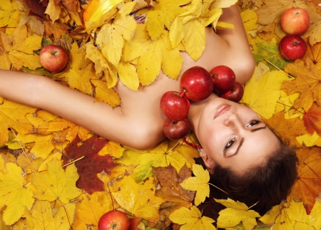 Beautiful girl Autumn lying over yellow leaves carpetの写真素材