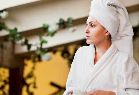 Attractive young woman in batherobe relaxing after shower at the terraceの写真素材