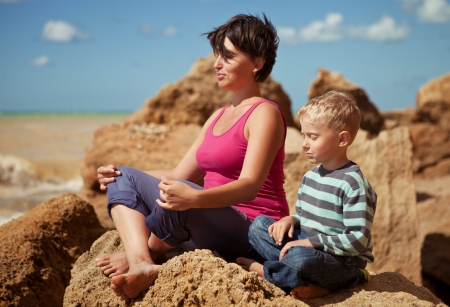 Mother and son in sitting relaxation pose at sea coastの写真素材