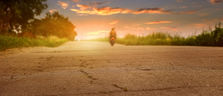 Sunset desserted highway with biker silhouetteの写真素材