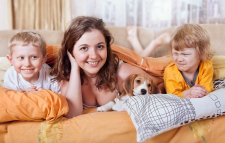 Brother and sisters playing in bed with beagle puppyの写真素材