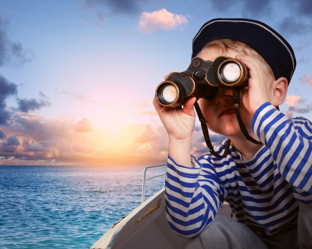 Little boy in sailor's uniform with binocular in the boatの写真素材