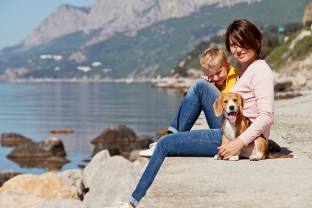 Happy mother and son sitting on the quay with beagle puppy の写真素材