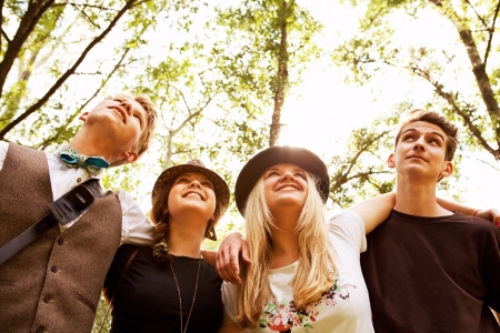 Four happy teenage friends huging shoulders each othersの写真素材