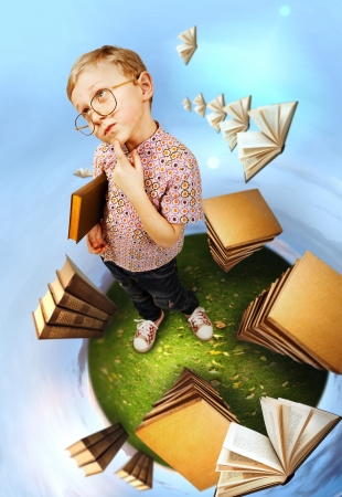 Clever little boy in glasses standing on abstract book planetの写真素材