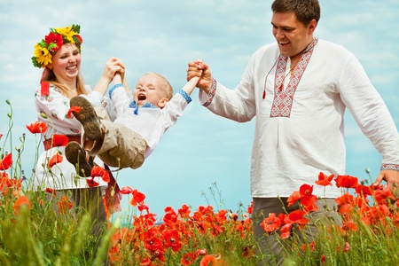 Parents playing with little son on the poppies fieldの写真素材