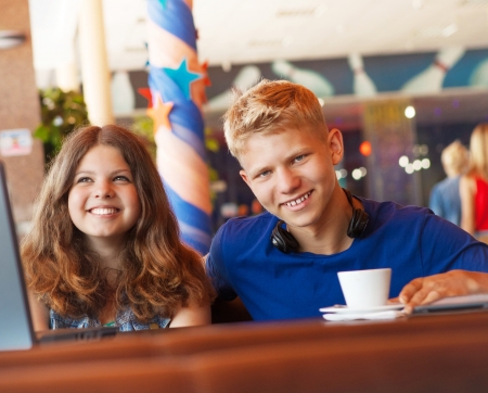 Cheerful teenage couple spend time in cozy cafeの写真素材