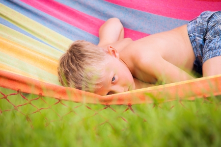 Summer leisure  Calm little boy quietly  lying in hammockの写真素材