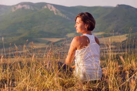 Calm smiling woman facing the rising sun into the mountain localityの写真素材