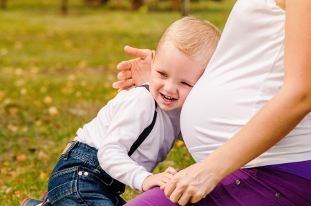 Happy smiling little son near pregnant mom tummyの写真素材