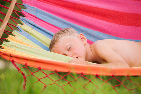 Pretty little boy resting in hammock in summer hot dayの写真素材