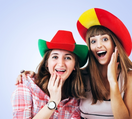 Two happy screaming girls football fans in bright hatsの写真素材