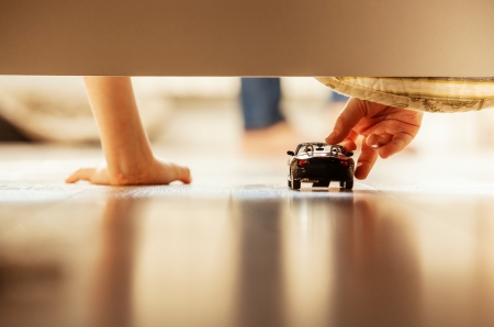 Boy playing with toy car overhang from the bedの写真素材