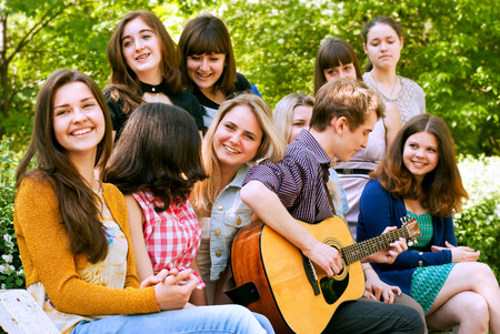 Teen boy singin by guitar for girlsの写真素材