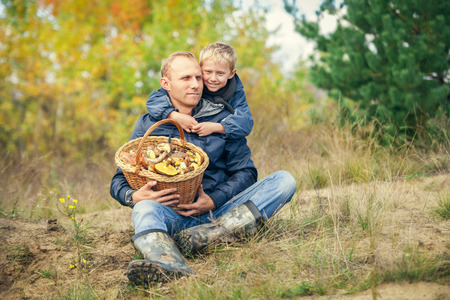 Father and son with full basket of mashrooms on the forest gladeの写真素材