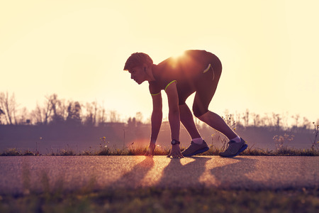 Athletic man starting evening jogging in sun raysの写真素材
