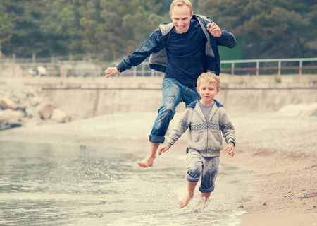 Father with son running on the sea surf lineの写真素材