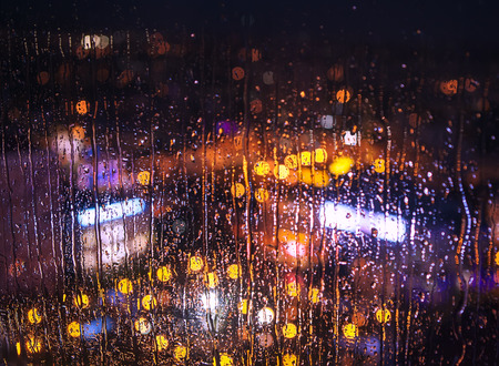Night city lights behind rainy windowの写真素材