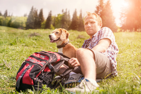 Man with his dog rest on the mountain hillの写真素材