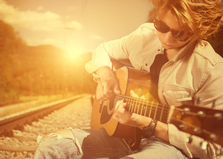 Guy with guitar on the railwayの写真素材