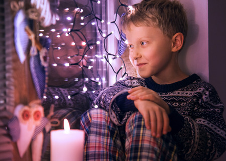 Boy waiting for Santa on the window with Christmas Lightsの写真素材