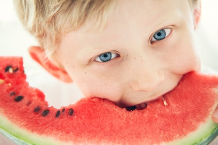 Blue eyes boy with watermelonの写真素材