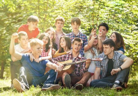 Group of happy young people singing with guitar togetherの写真素材