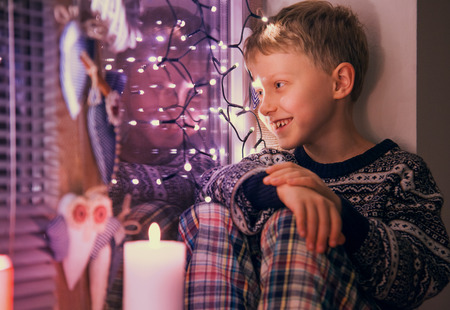 Boy waiting Santa on the window with Christmas Lightsの写真素材