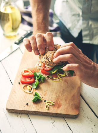 Man hands take a sandwich with ham and vegetablesの写真素材