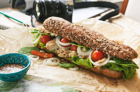 Big sandwich with chicken on the travel photographer tableの写真素材