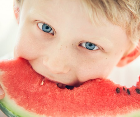 Blue eyes boy with watermelonの写真素材