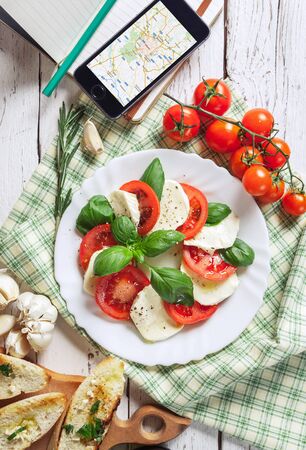 Italian traditional Caprese salad with traveler smartphone map to Italyの写真素材