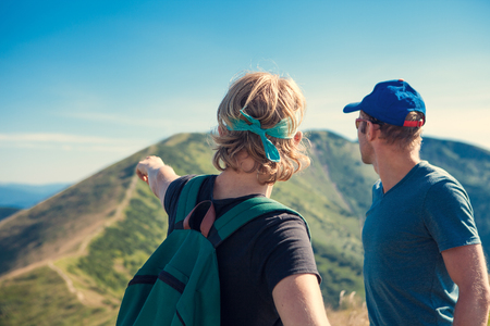Two travelers discuss about itinerary on the top of mountain hillの写真素材