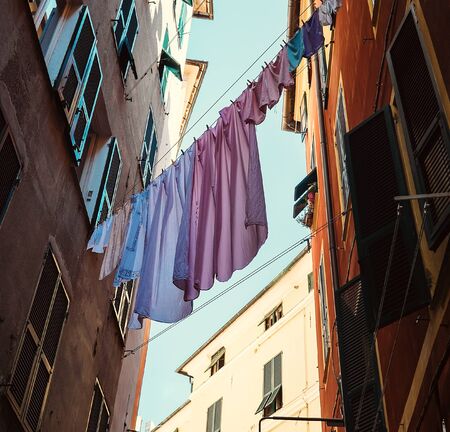 Colorful linen dry on rope between houses on old italian streetの写真素材